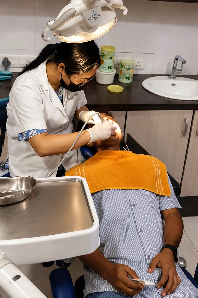 Dentist examining a patient's teeth with an intraoral camera at Sanjeevani Dental Clinic